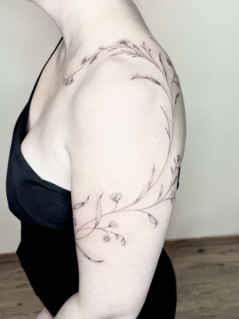 dünne linien tattoo, floral tattoo, freehand tattoo, tattoo auf die haut direkt gezeichnet, vergissmeinnicht tattoo in fineline stil auf der shulter und um den arm, delikate blüte Tattoo, elegante ranke tattoo am Arm, dünne blätter Tattoo, fineline Tattoo Zürich