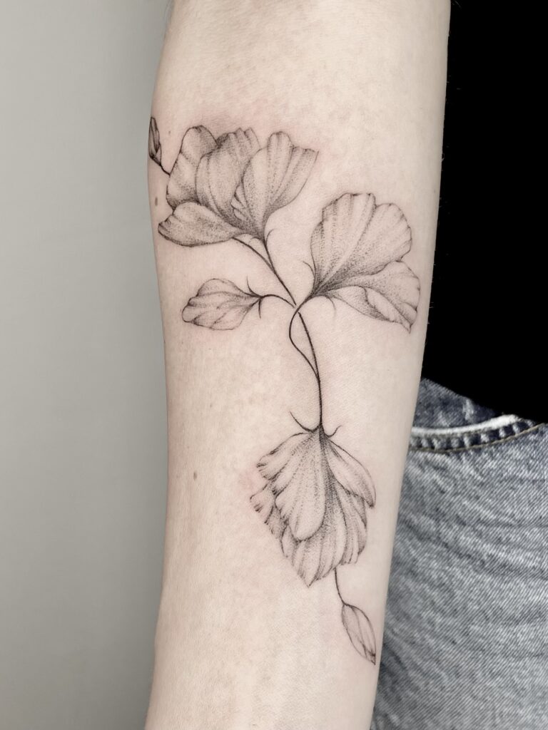 Fineline-Tattoo einer Sweet Pea-Blume (Duftwicke) auf dem Unterarm mit feinen Linien und sanften Dotwork-Schattierungen.