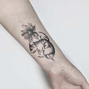 Tatto von einer Maus im Mikrorealismus stil, die eine kamillenblüte in den Pfoten hält